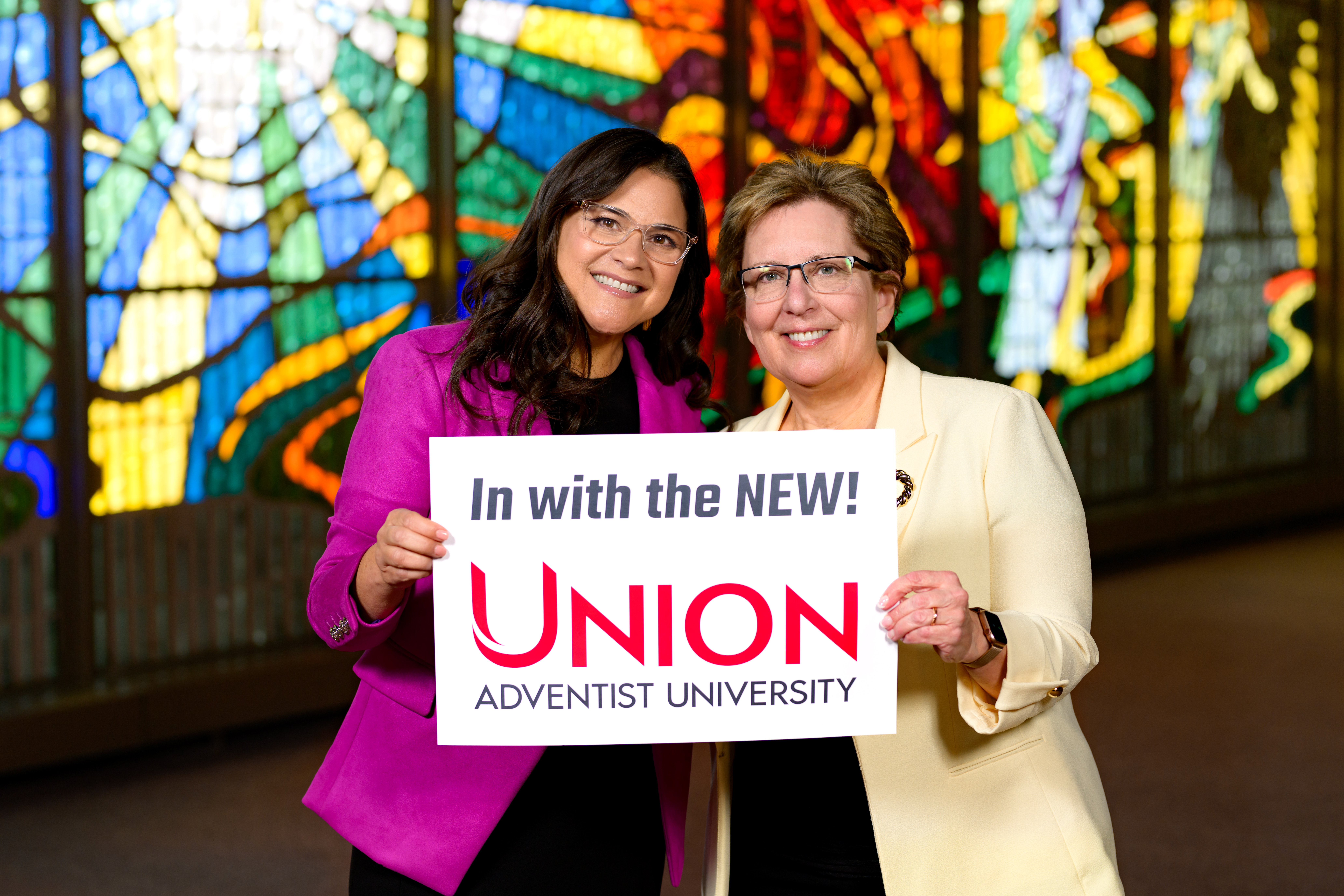 Photo of Dr. Bazan with Dr. Sauder holding a sign saying "In with the new! Union Adventist University"