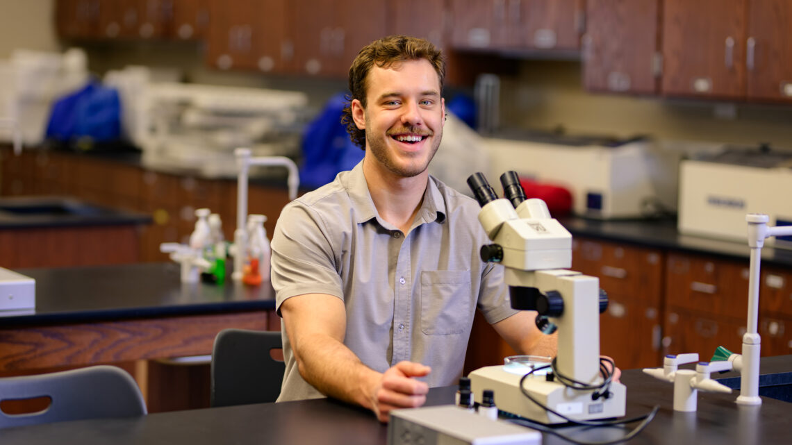 Photo of Adam Anderson with a microscope