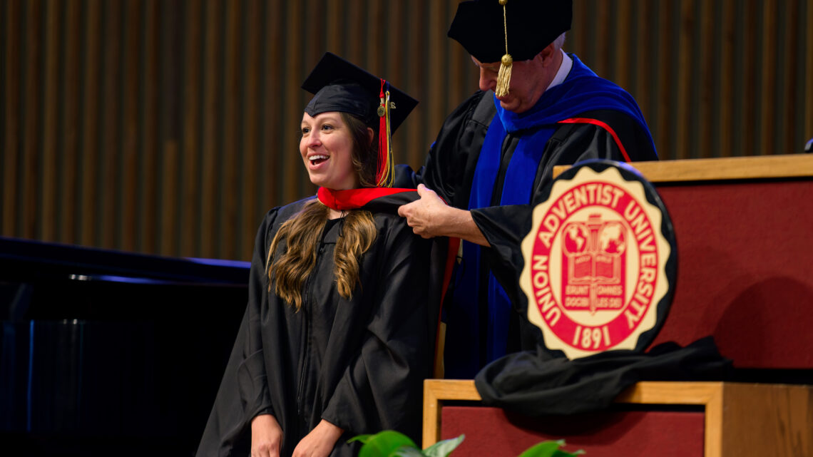 Photo of Mollie Dupper receiving her graduation hood from Dr. Rich Carlson.