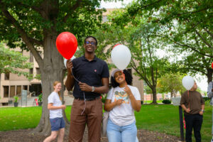 Photo of Yann Birasa and Umeran Waktole holding balloons.